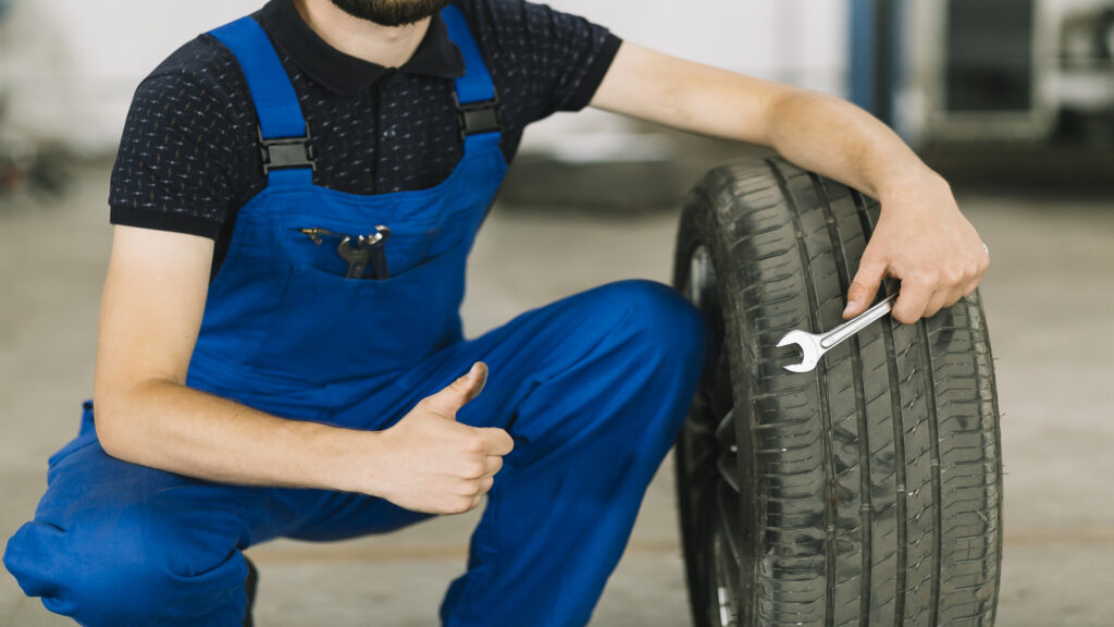 mecanico de uma Revenda de pneus oficial de pneus goodyear aguaixado ao lado de pneu